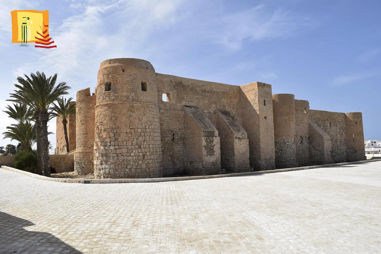 Remparts de pierre du fort Ghazi Mustapha avec ses tours rondes et un palmier a Houmt Souk Djerba