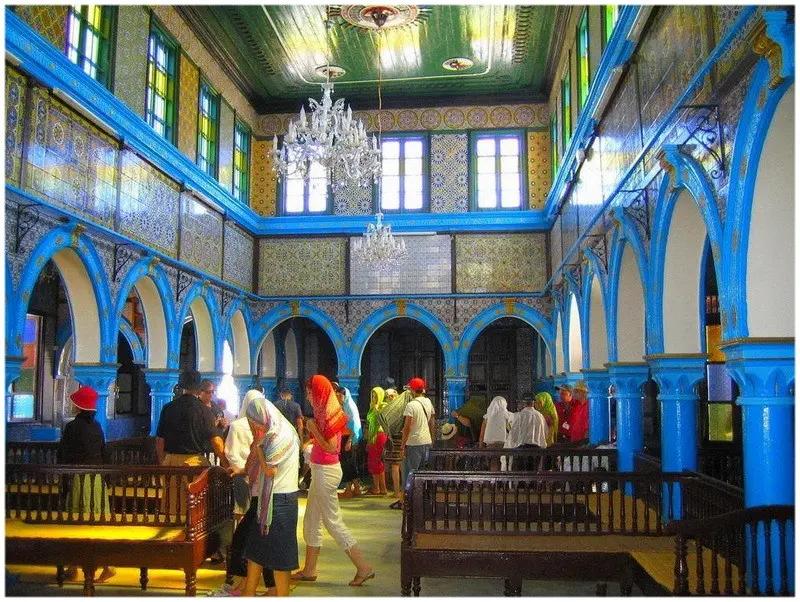 Interieur de la synagogue de la Ghriba avec arcades bleues zellige et visiteurs a Djerba